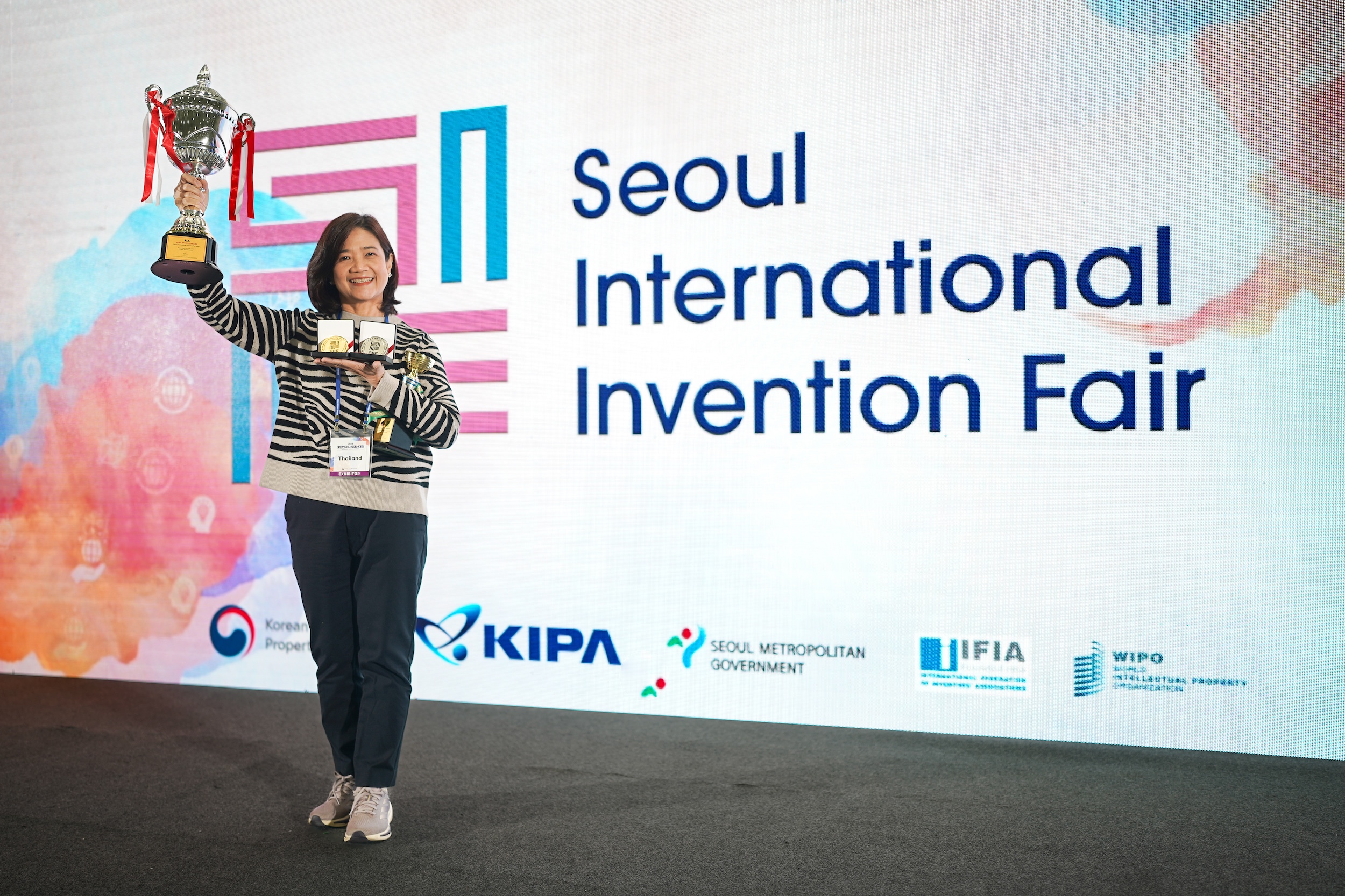 Professor Suchada Sukrong, Ph.D., Executive Director of CSII, proudly holds her awards on stage at the Seoul International Invention Fair 2024, celebrating Herb Guardian’s gold and silver prize-winning innovations in eco-friendly skincare solutions.