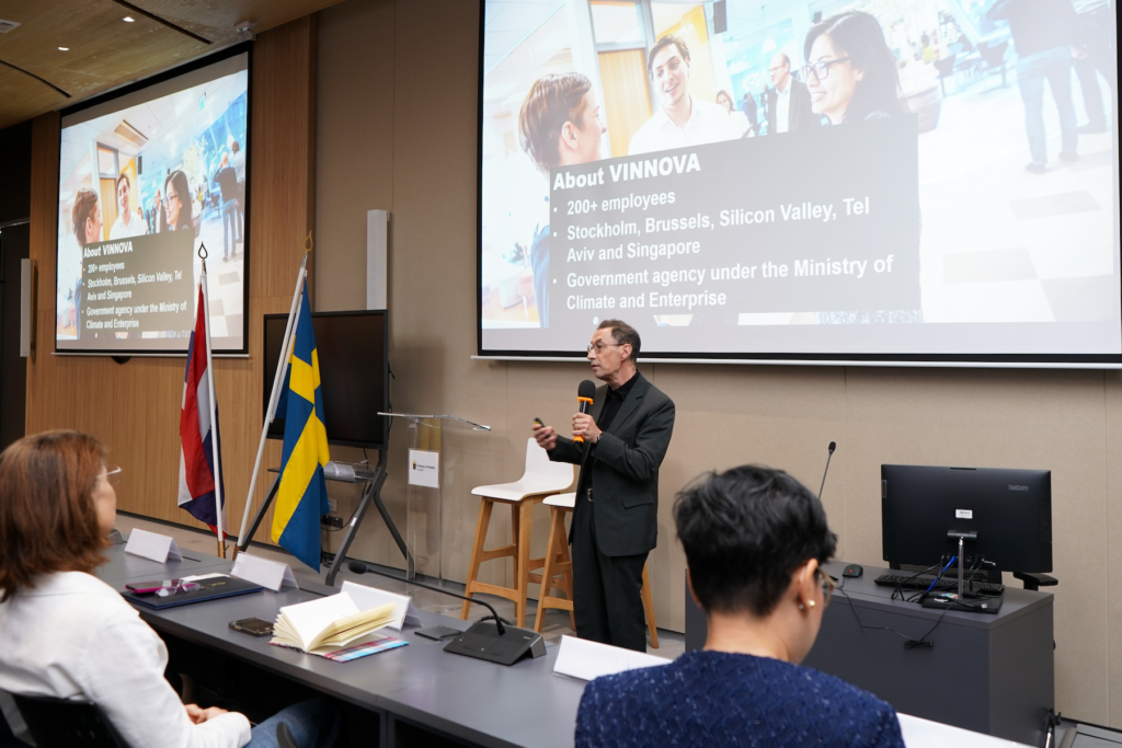 Mr. Kjell Håkan Närfelt, Chief Strategy Advisor at Vinnova, delivering a lecture at Chulalongkorn University’s CSII, about Swedish Innovation Ecosystem, with the Swedish and Thai flags and a presentation slide about Vinnova in the background. Attendees are seated and listening attentively.